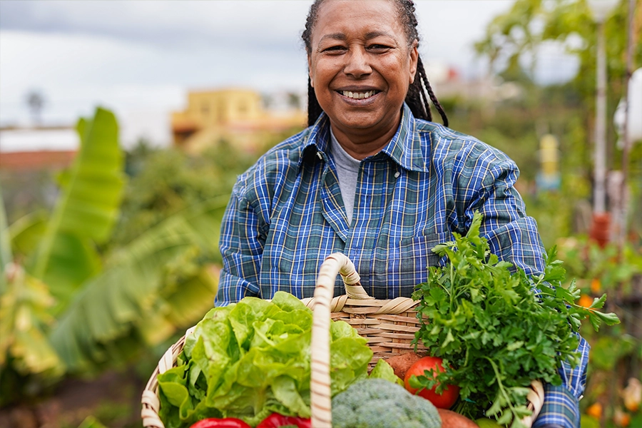 happy woman holding fresh harvested vegetable at house garden